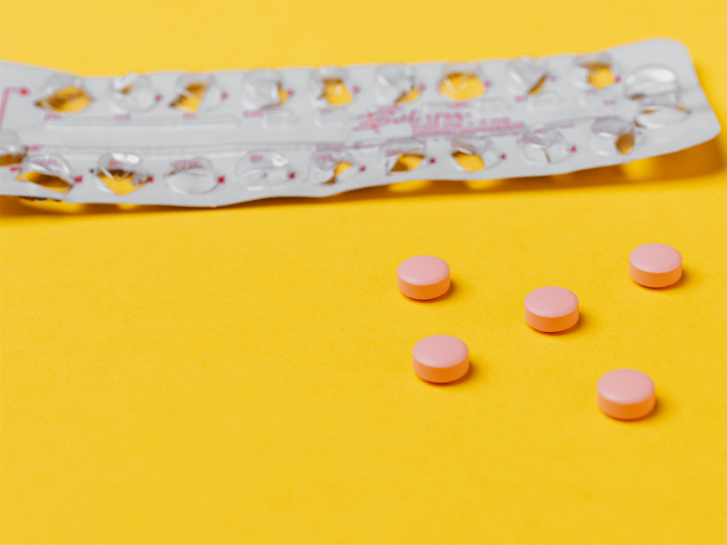 Blister packaging with loose pink pills next to it