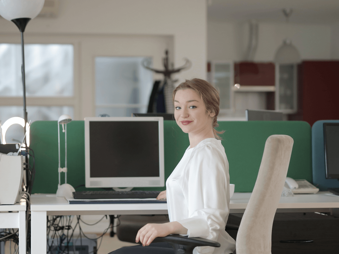 A female worker sits at her desk as she glances towards the camera