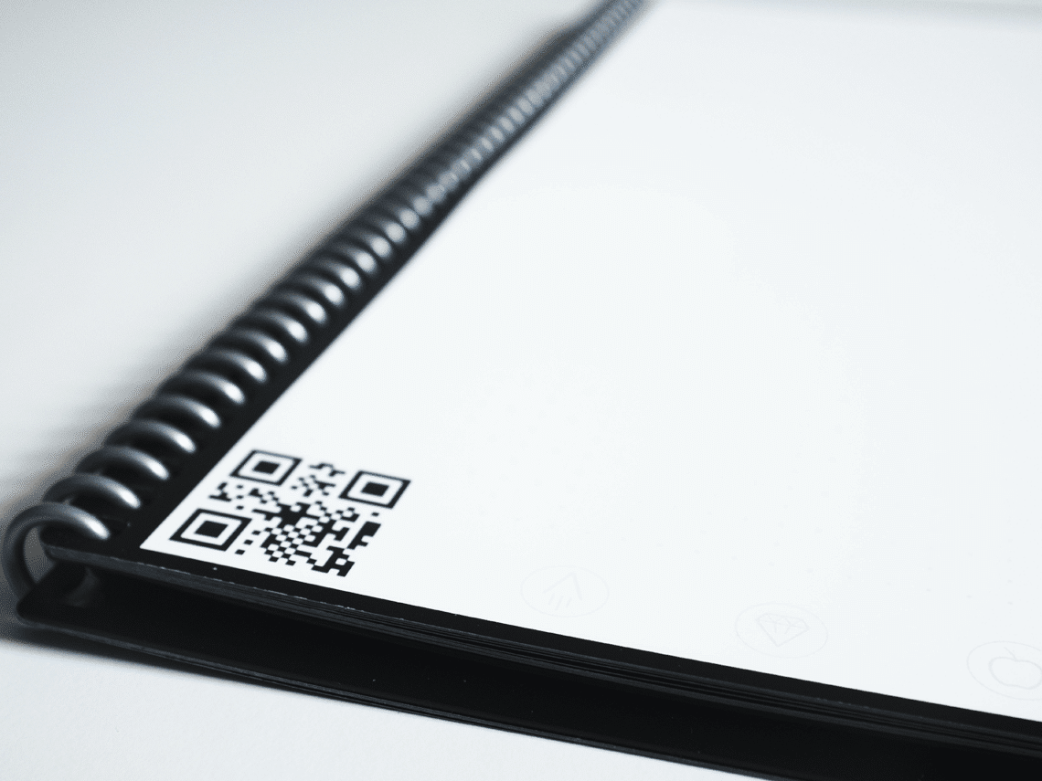 A spiral notebook with a QR Code on the bottom left