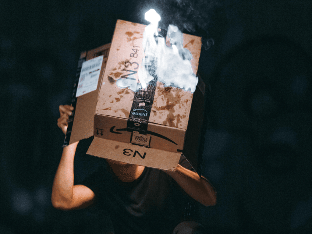 A man is holding a lit Amazon cardboard box in the air