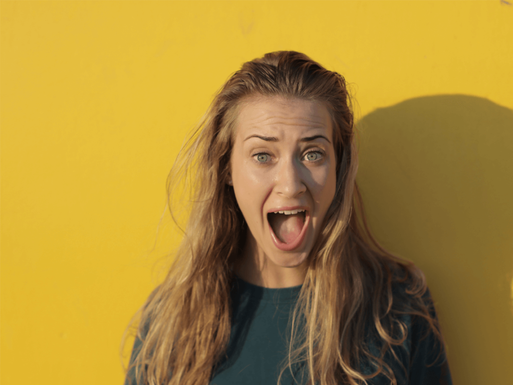 A young woman is looking surprised towards the camera