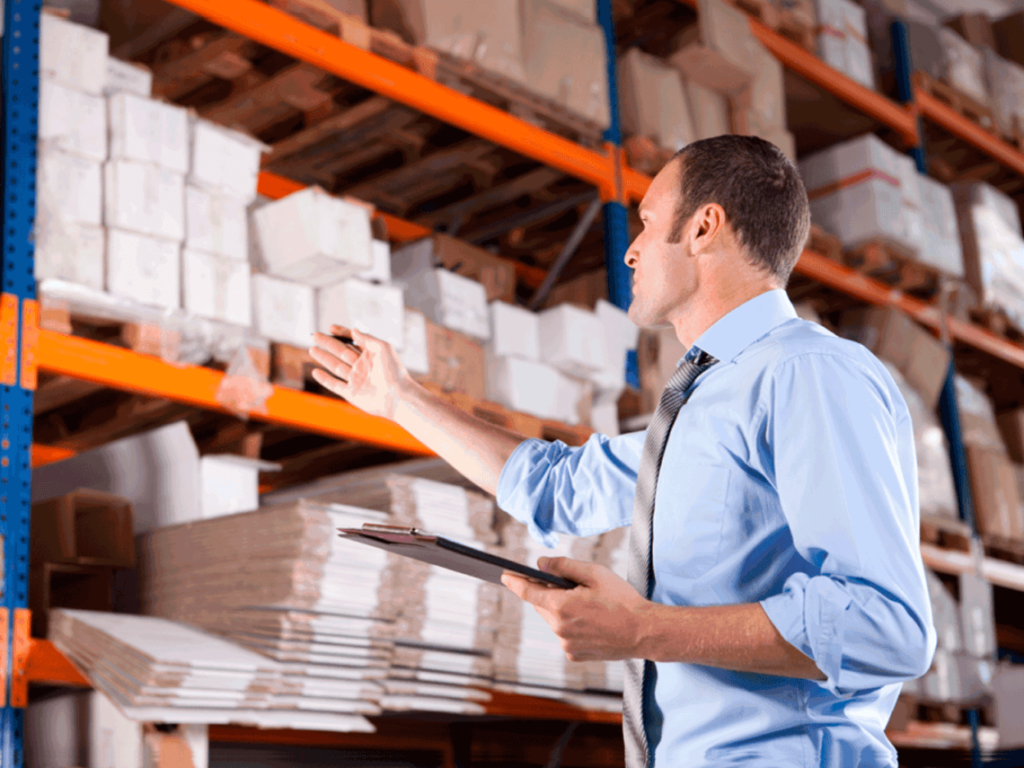 A man with a clipboard is going through his warehouse inventory