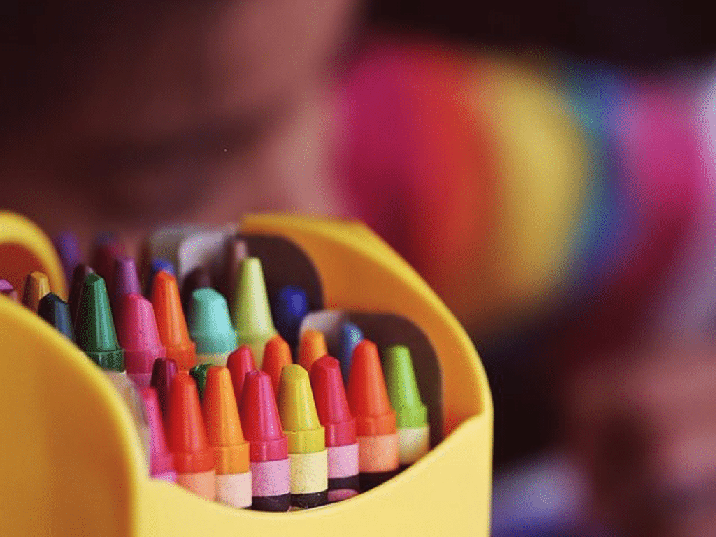 A yellow box of crayons with the colorful tips pointing out of the opening