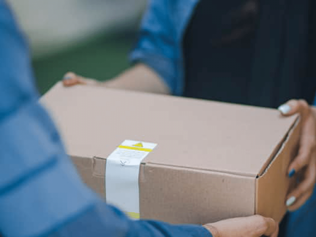 A person is handing off a box to another individual