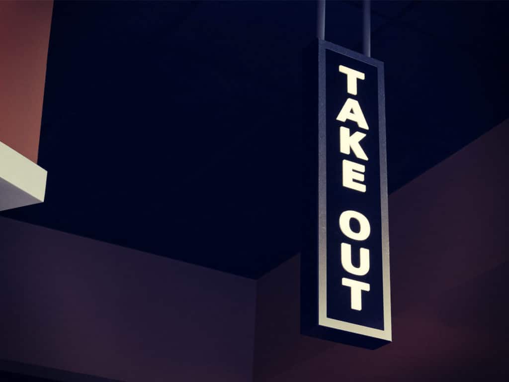 A large Take Out sign hangs in a dim room