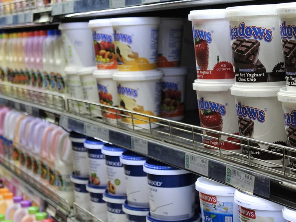 A grocery store shelf stocked with different brands of yogurt