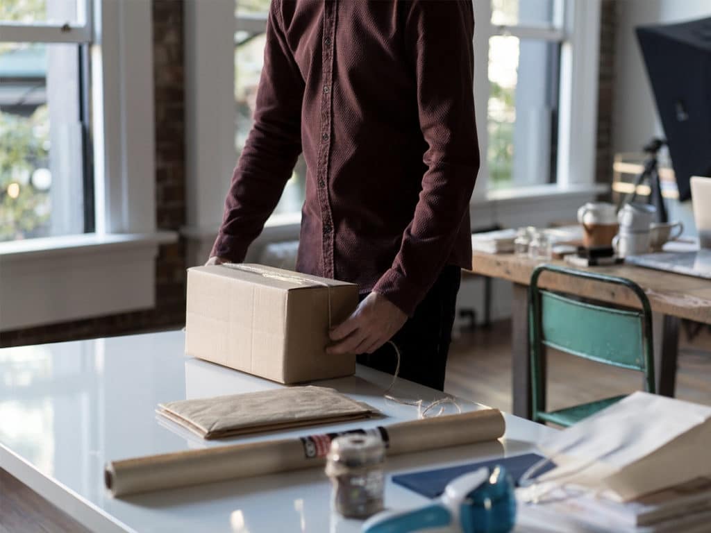 A man stands at a counter packaging an item to ship