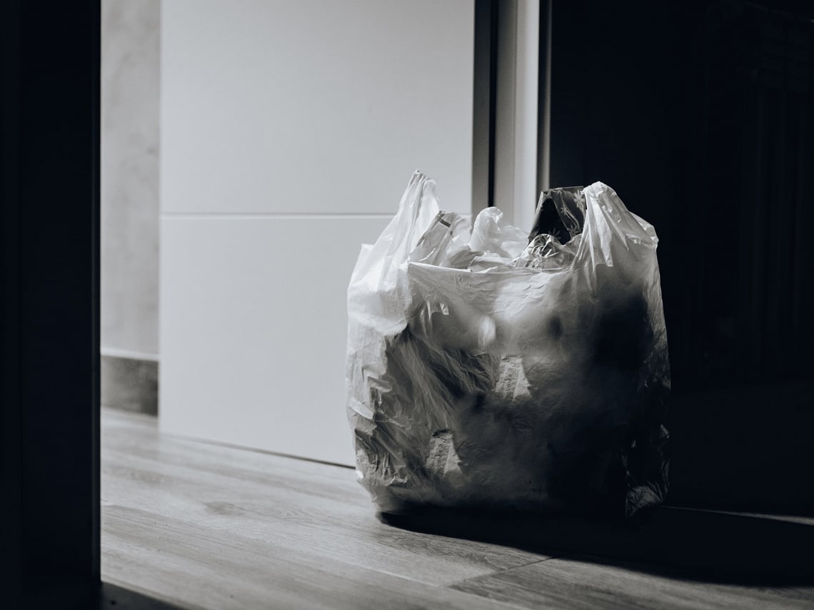 A large white garbage bag filled with trash sitting in a doorway