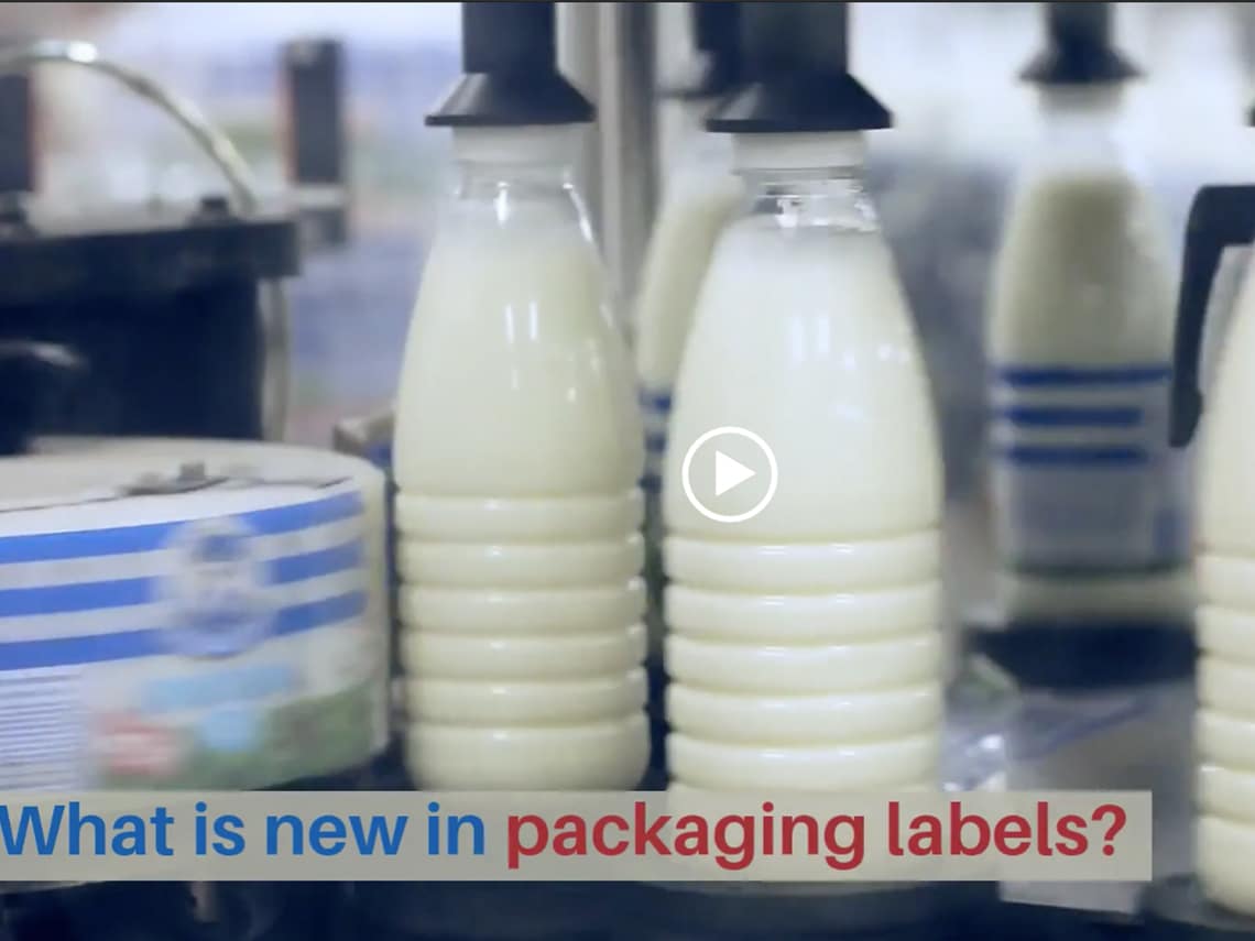 Bottles of milk are being packaged on a conveyer belt with the caption"What is New in Packaging Labels?"
