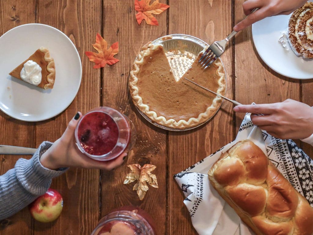 A thanksgiving table with a pie, loaf of bread, and autumn leaves