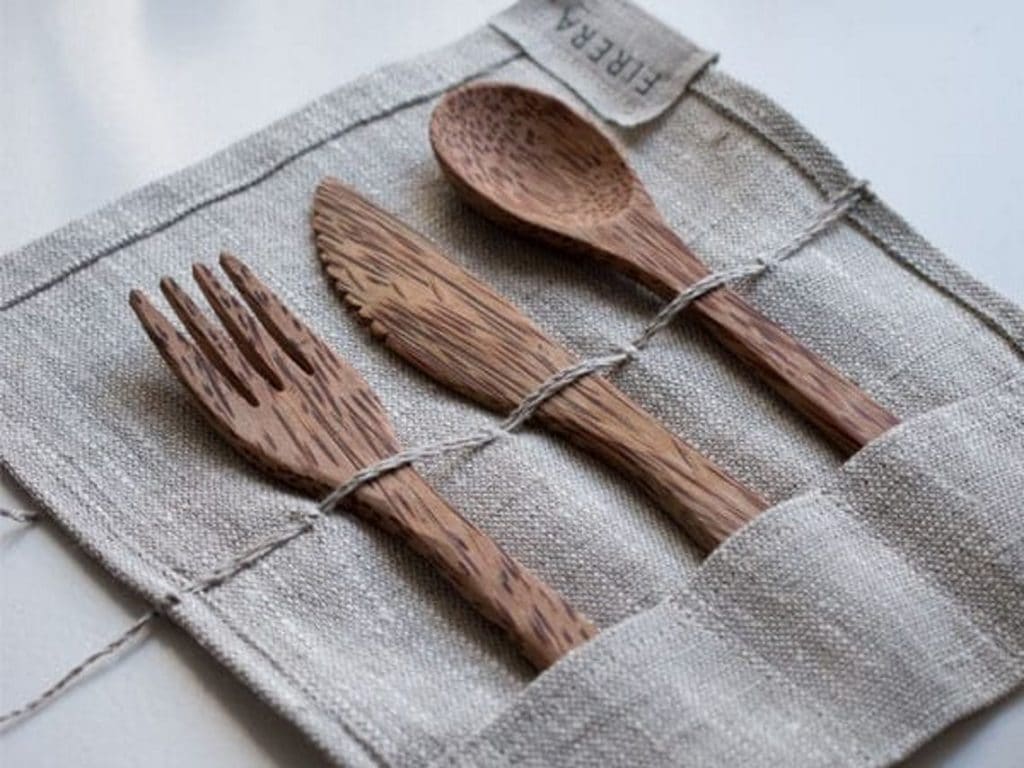 A grey cloth is laid out with wooden eating utensils in it's pockets