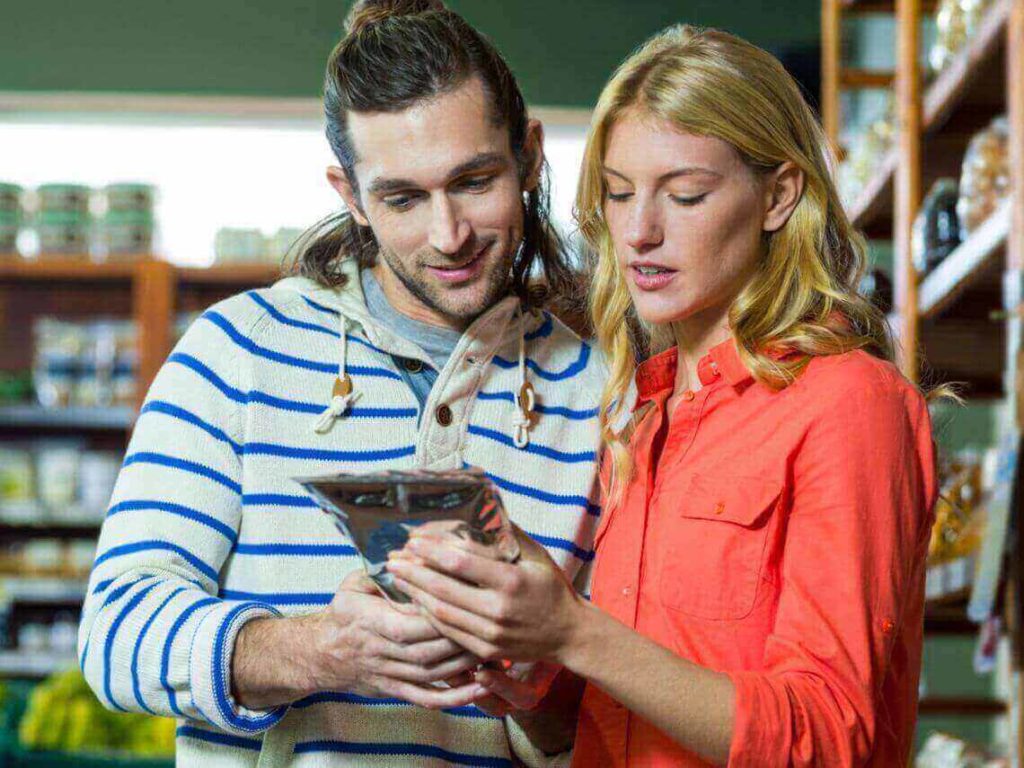 A man and a woman are in a grocery isle looking at branded packaging