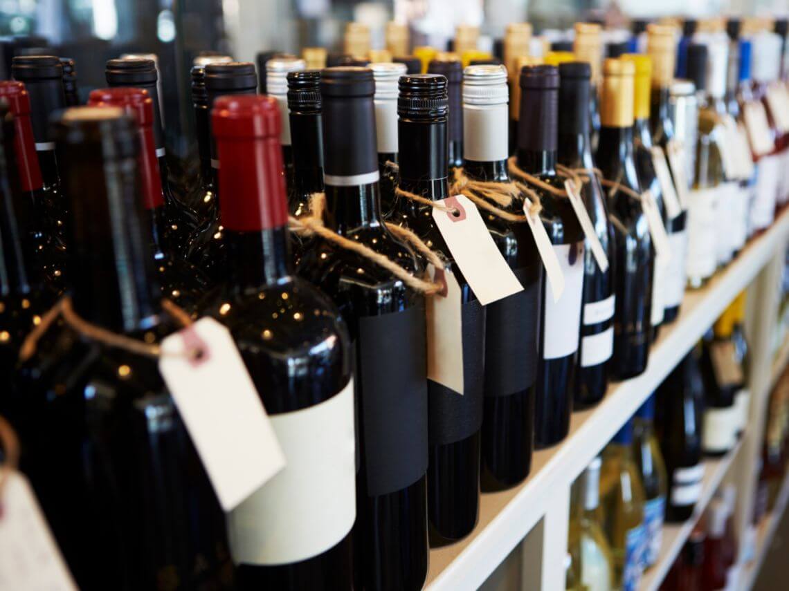 A row of wine bottles line a shelf showcasing it's alcohol packaging
