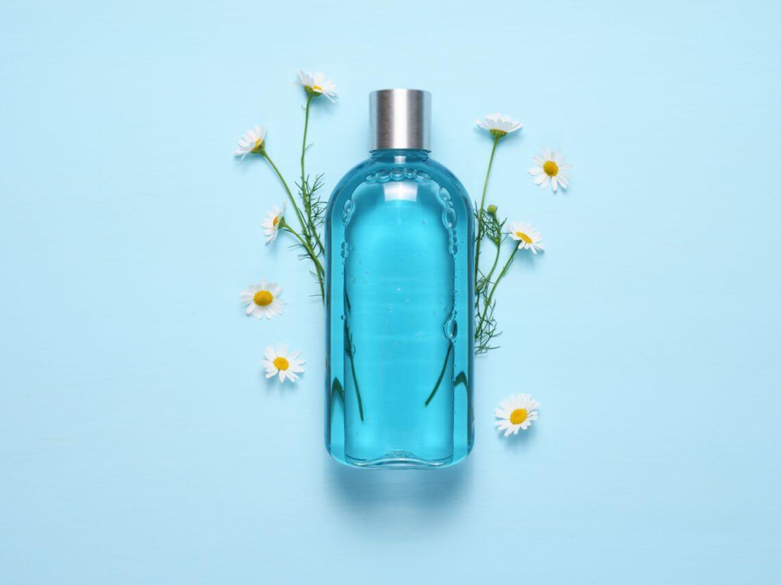 A light blue eco-friendly shampoo bottle surrounded by flowers