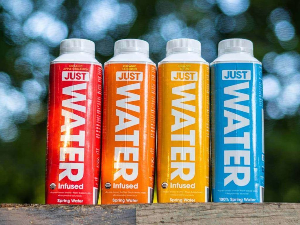 A row of colorful Just Water organic food packaging bottles sit on a table