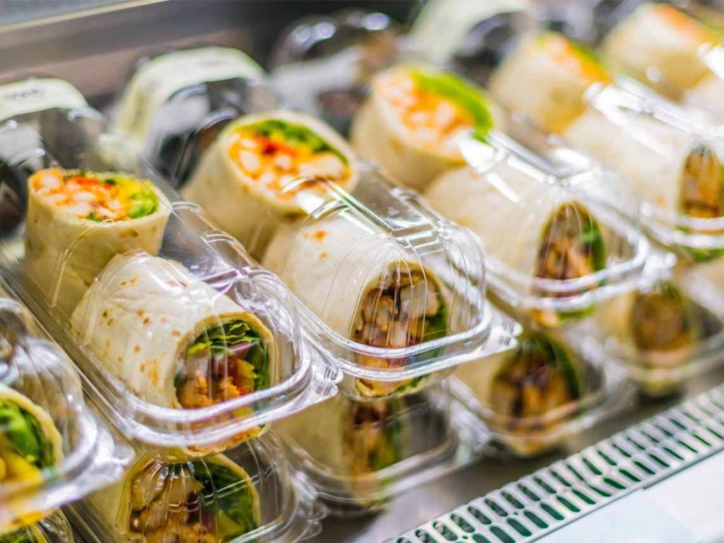 An assembly line of sandwich wraps inside thermoformed plastic clamshells