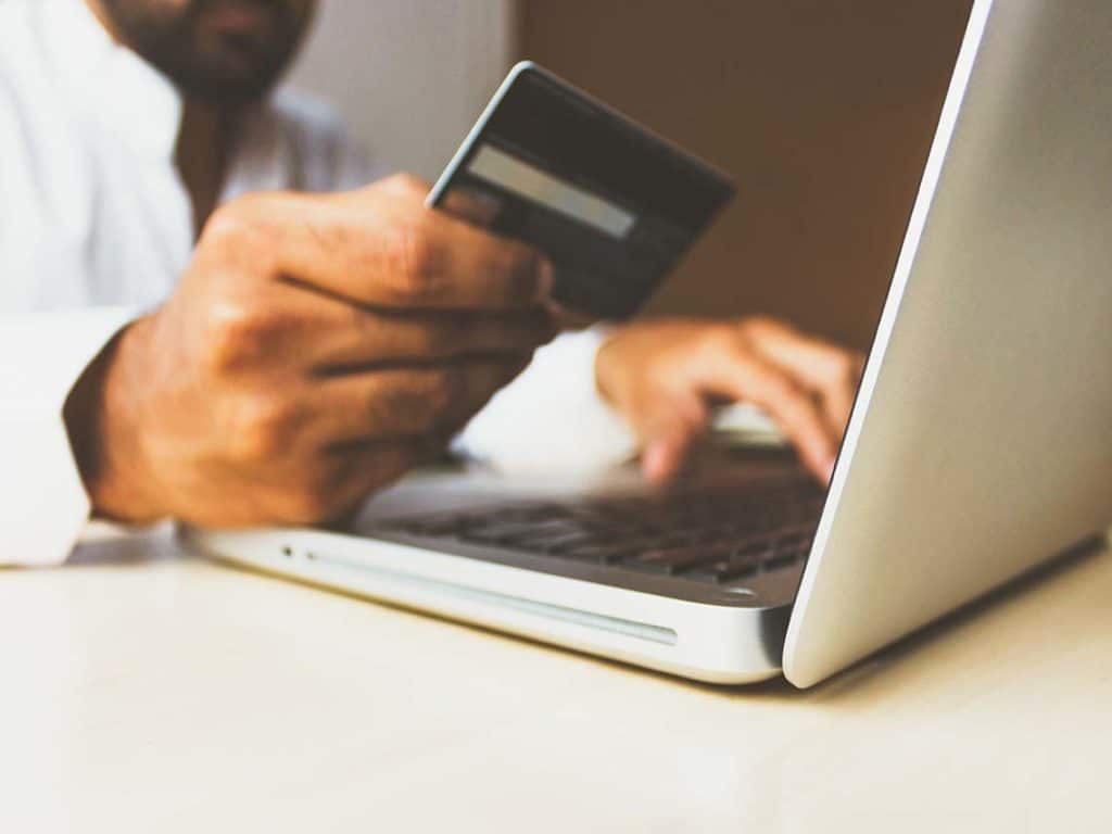 man on his computer with a credit card shopping online