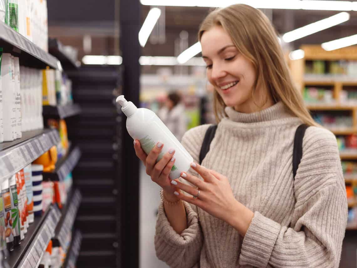 Young woman examines shampoo bottle that meets the FDA Beauty Labeling Requirements