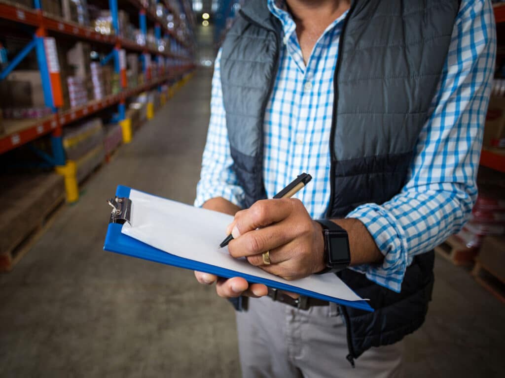 man in warehouse with clipboard doing a packaging consultation