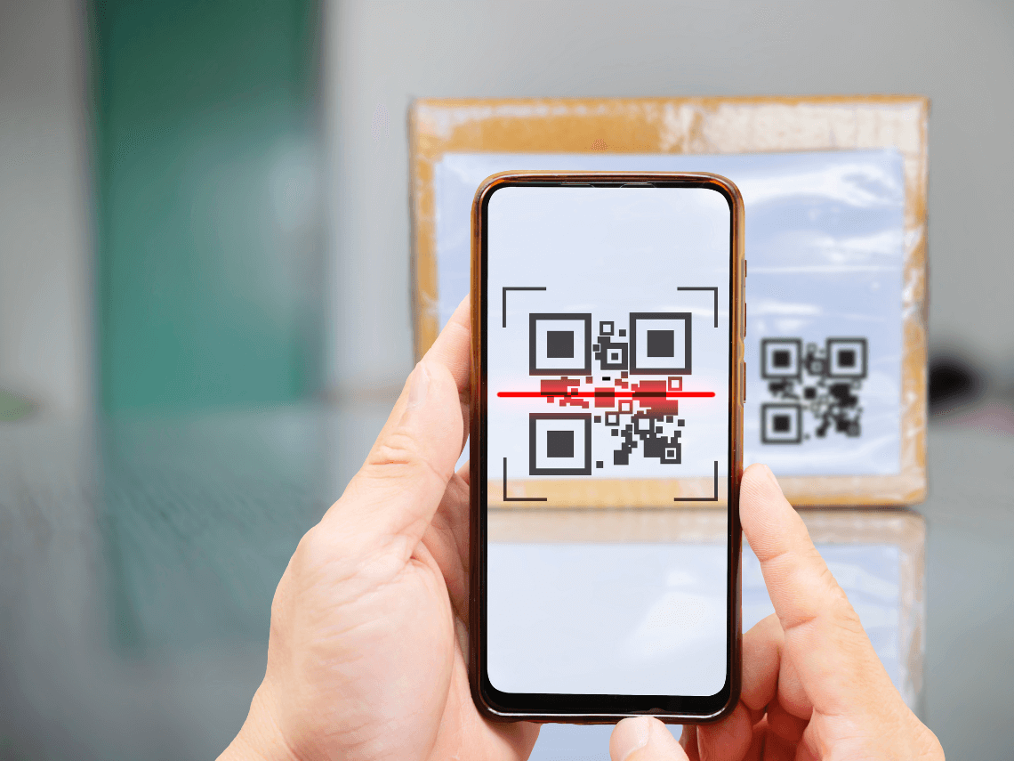 A person using a smartphone to scan a QR code on a box. The QR code is Smart Packaging.